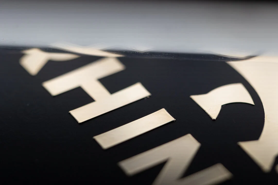 Close-up photograph showing the clear top transfer film being peeled away after applying an electroformed metal transfer sticker